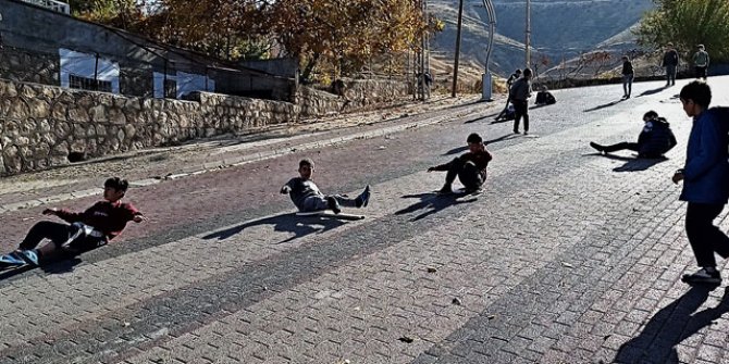 Henüz karın yağmadığı Gercüş'te çocuklar, yokuş aşağı tahta parçalarıyla kayıyor