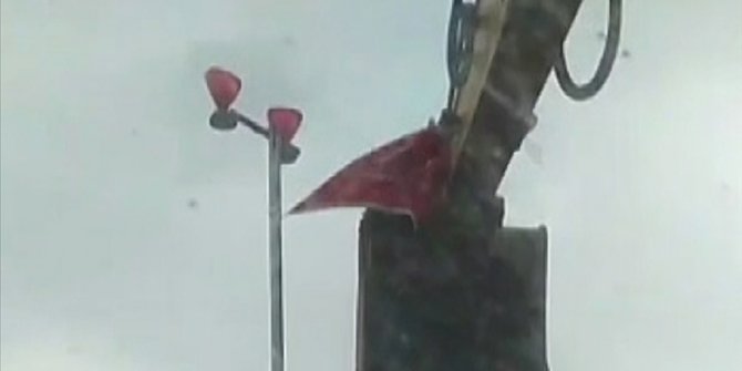 Antalya'da bir vatandaş rüzgarda kopmak üzere olan Türk bayrağını kepçeye çıkarak yerinden aldı