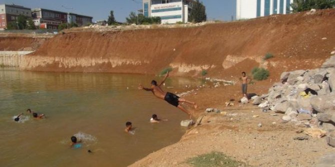 Çocuklar, inşaat temelini dolduran kirli suda yüzüyor